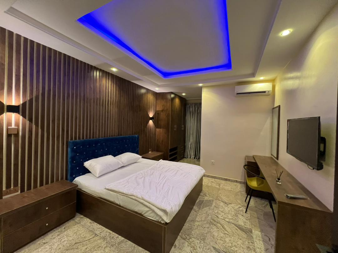 Executive Room sleeping area with upholstered headboard, desk, television and air conditioning
