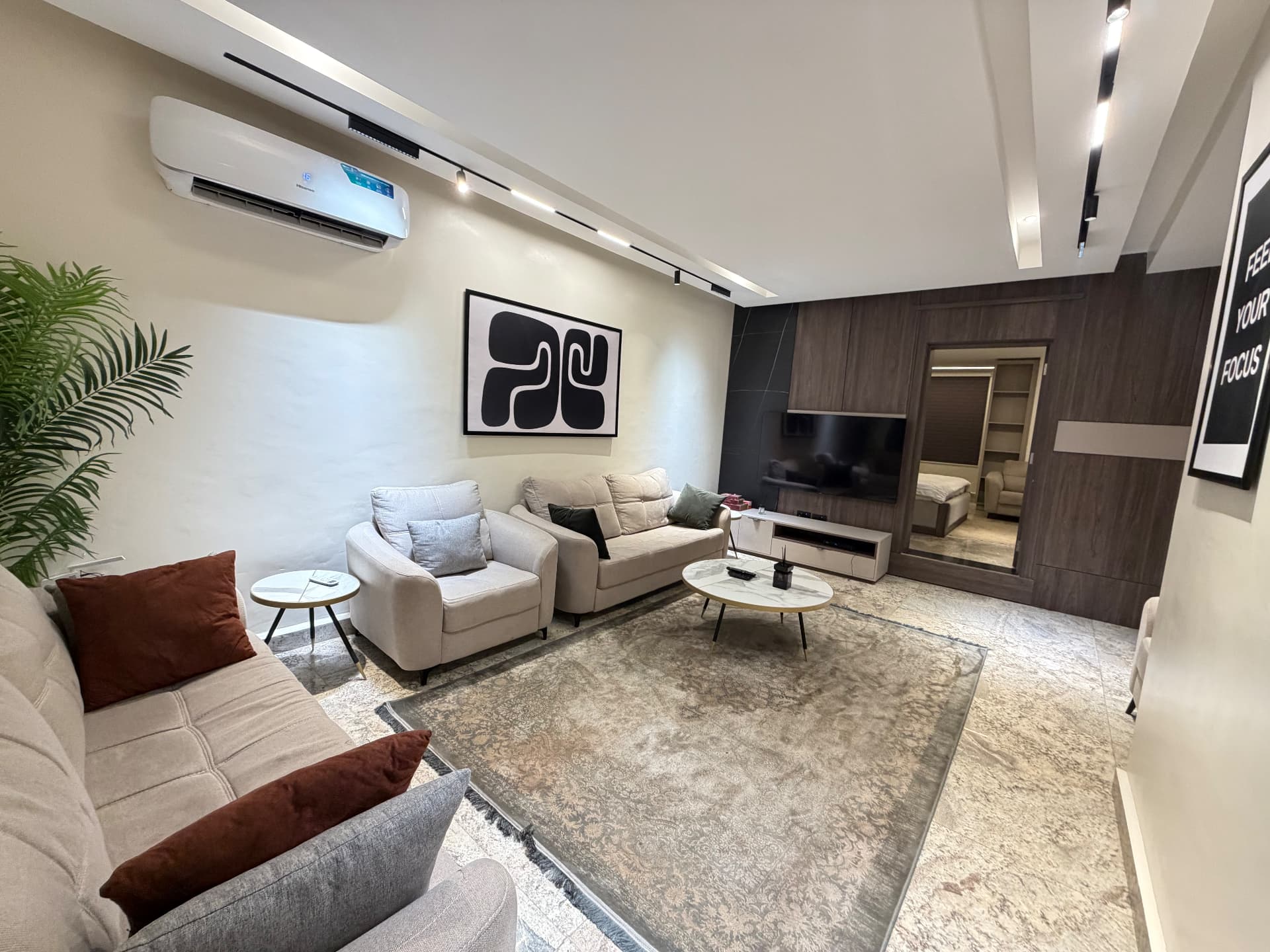 Second angle of the living room showing seating, television wall and air conditioning