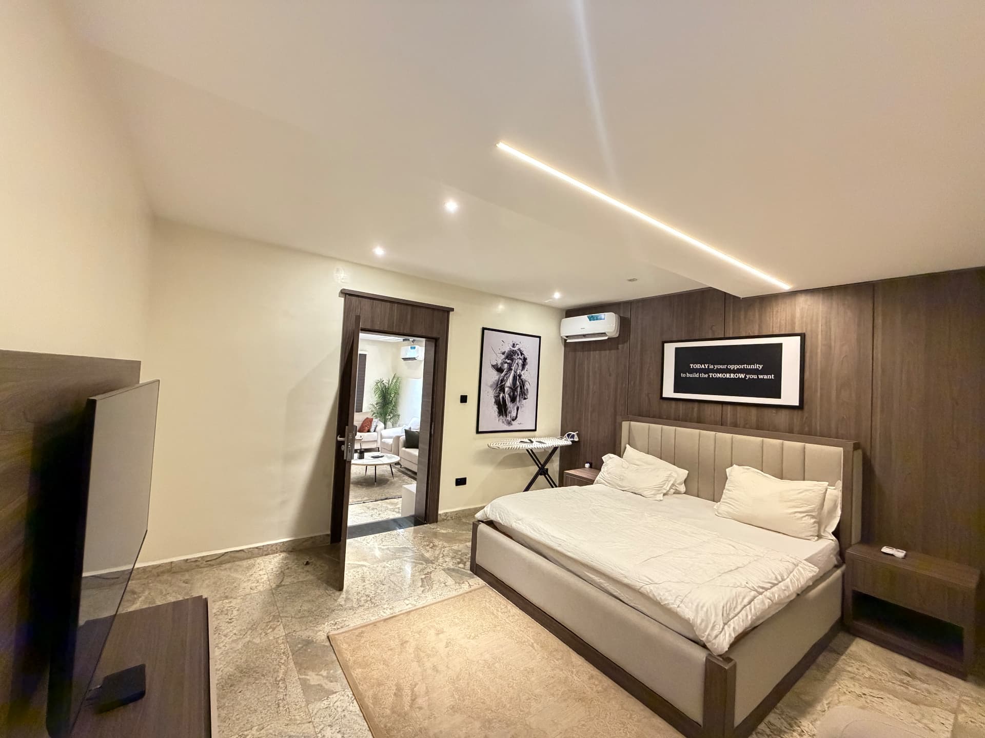 Bedroom view towards the living area, with television and framed artwork