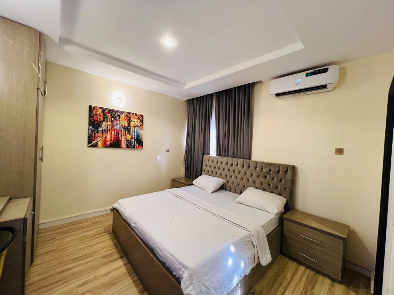 Sleeping area of the Ambassador Retreat with fitted wardrobe, bedside drawers and framed artwork