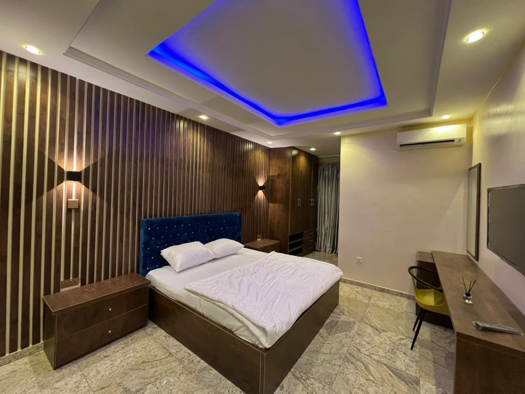 Executive Room in an Aston shared residence, Apo Legislative Quarters, Abuja — bed, wall-mounted television, work desk and fitted wardrobe