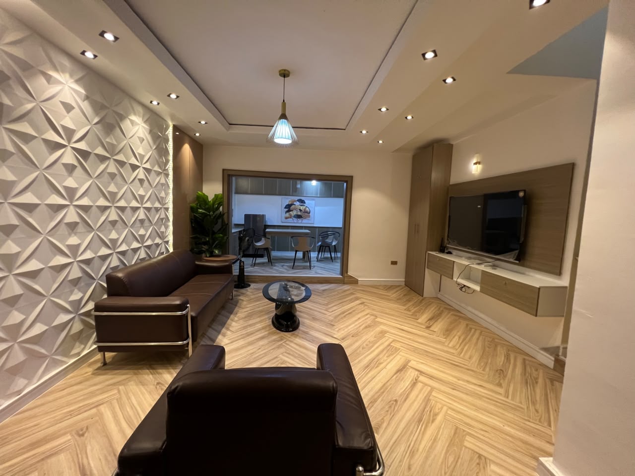 Shared living room of the Aston residence with seating, wall-mounted television and adjoining dining area