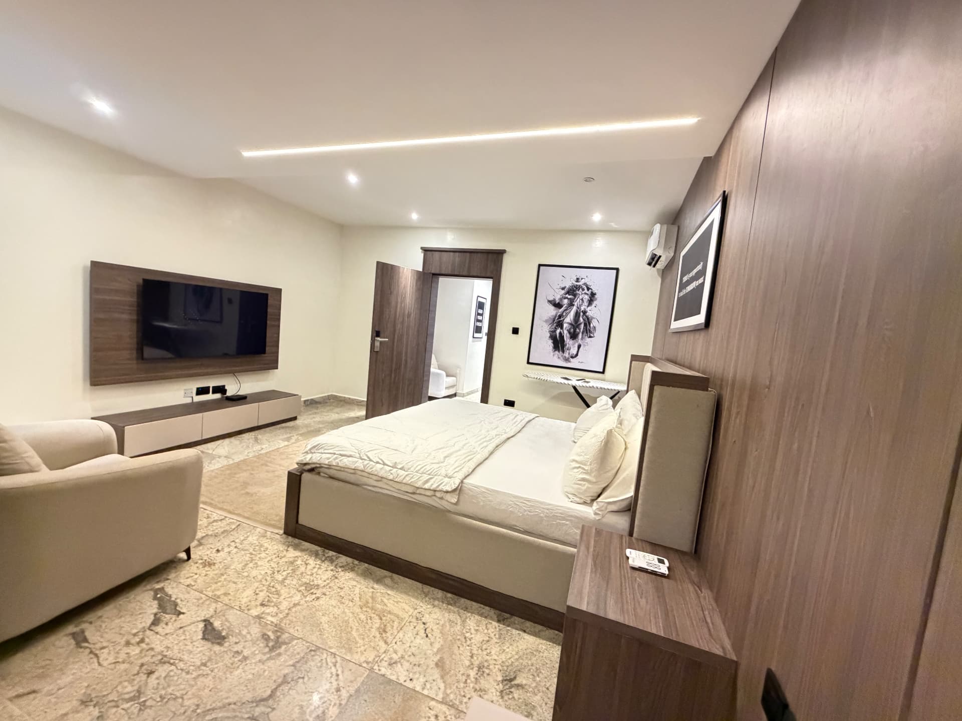 Bedroom view showing the wall-mounted television, seating and wardrobe wall