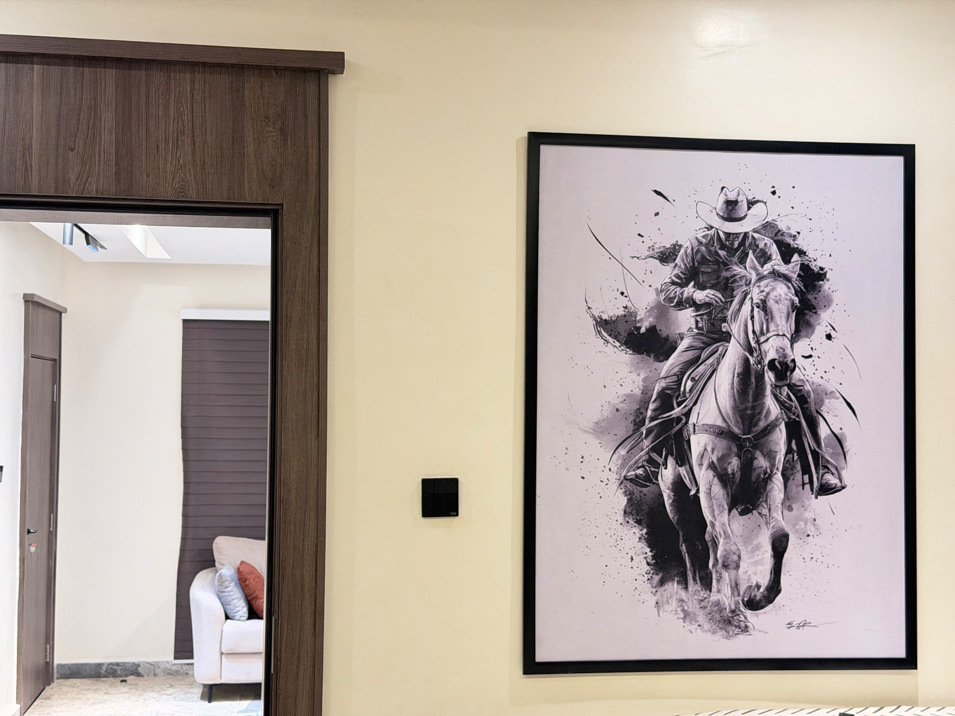 Hallway with framed artwork beside the doorway into the living area